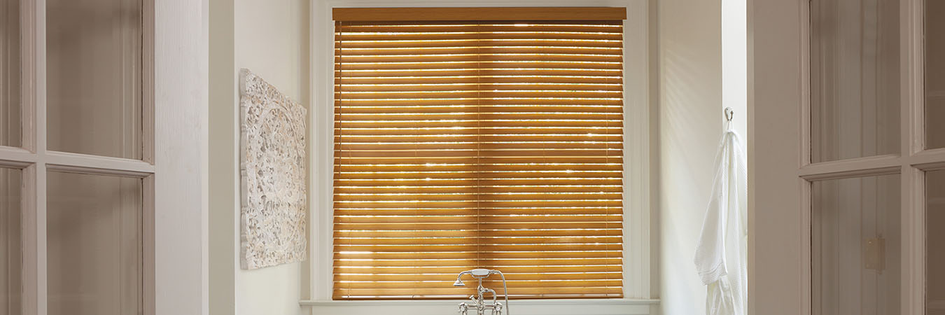 Light faux wood blinds above a bathtub